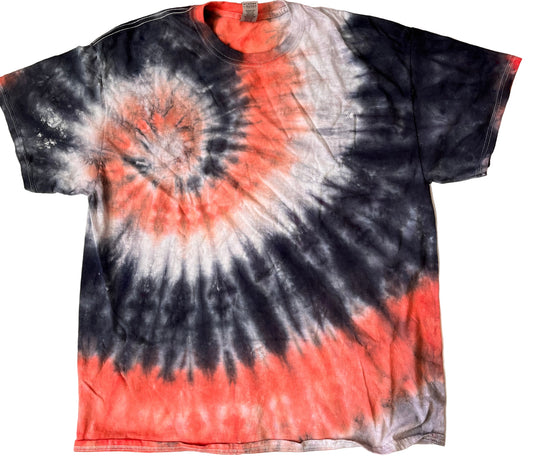 Tie-dye t-shirt with black, orange, and white spiral pattern on a beige background