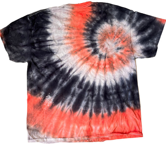 Tie-dye t-shirt with black, red, and white spiral pattern on a beige surface.